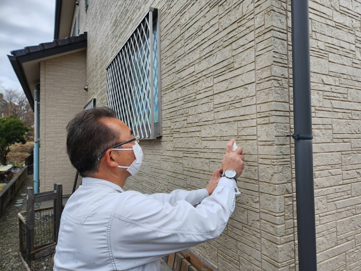 石積み調の外壁を手で触れて、劣化の有無を確認するスタッフ