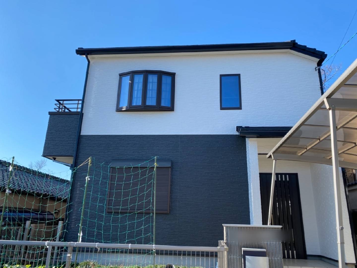 白とダークグレーのツートンカラーで塗装した戸建て住宅