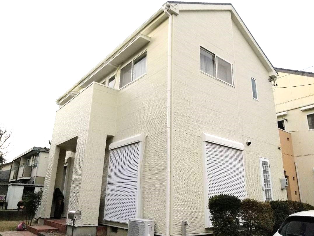 オフホワイトの外壁に塗装された二階建ての戸建て住宅