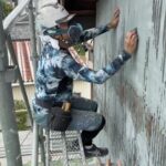 トタン外壁のケレン作業を行う職人加茂